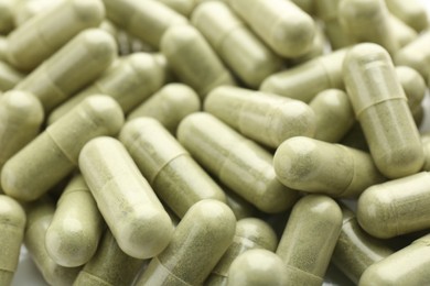 Light green vitamin capsules as background, closeup