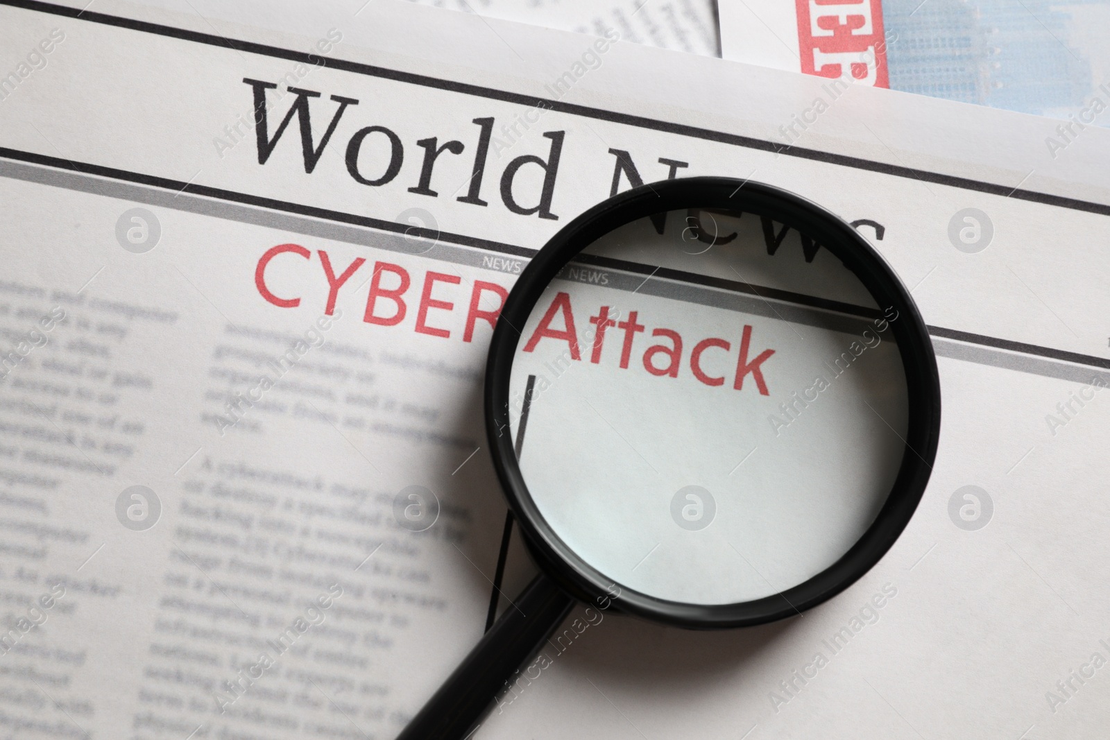 Photo of Newspaper with headline CYBER ATTACK and magnifying glass, top view