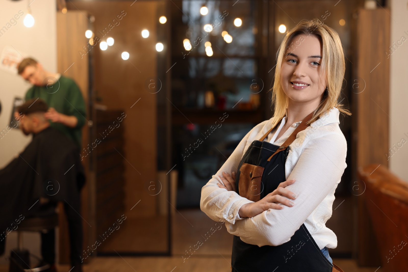 Photo of Portrait of professional hairdresser wearing apron in beauty salon, space for text