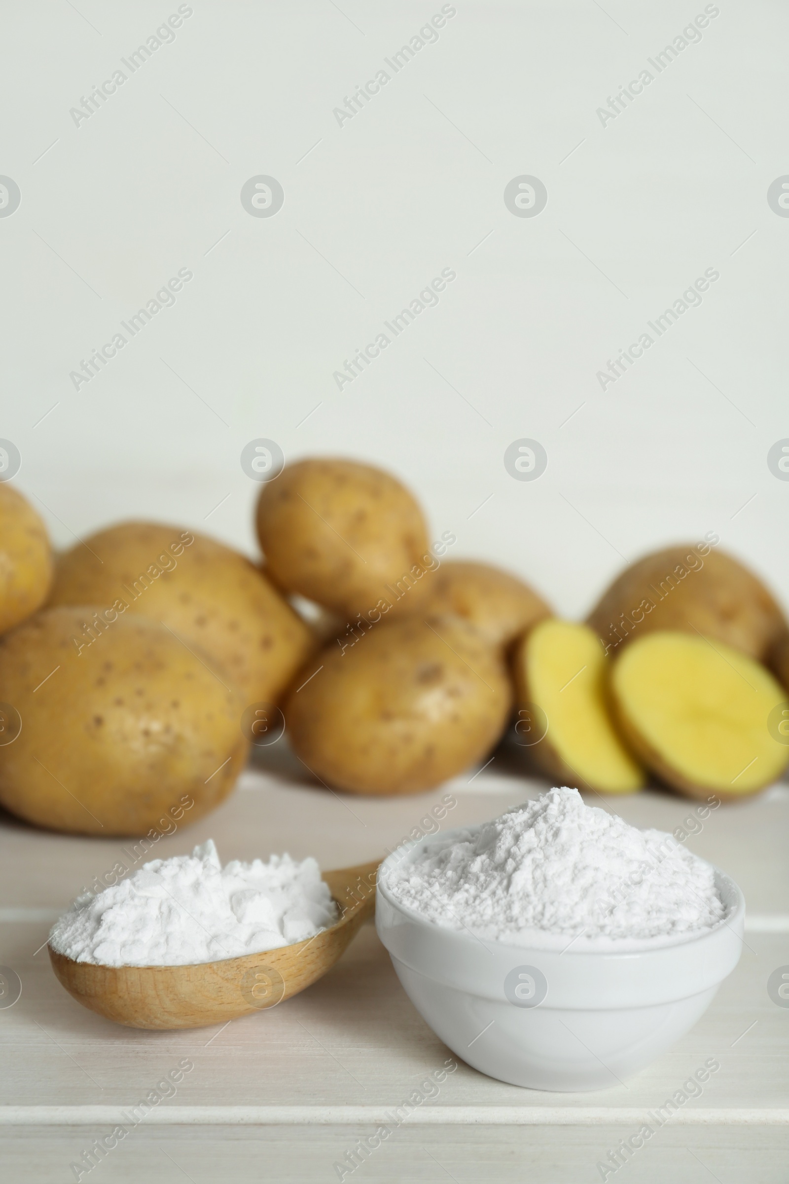 Photo of Starch and fresh raw potatoes on white wooden table. Space for text