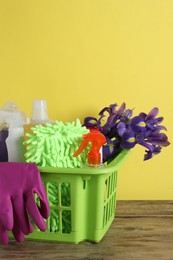 Spring cleaning. Basket with detergents, flowers and tools on wooden table