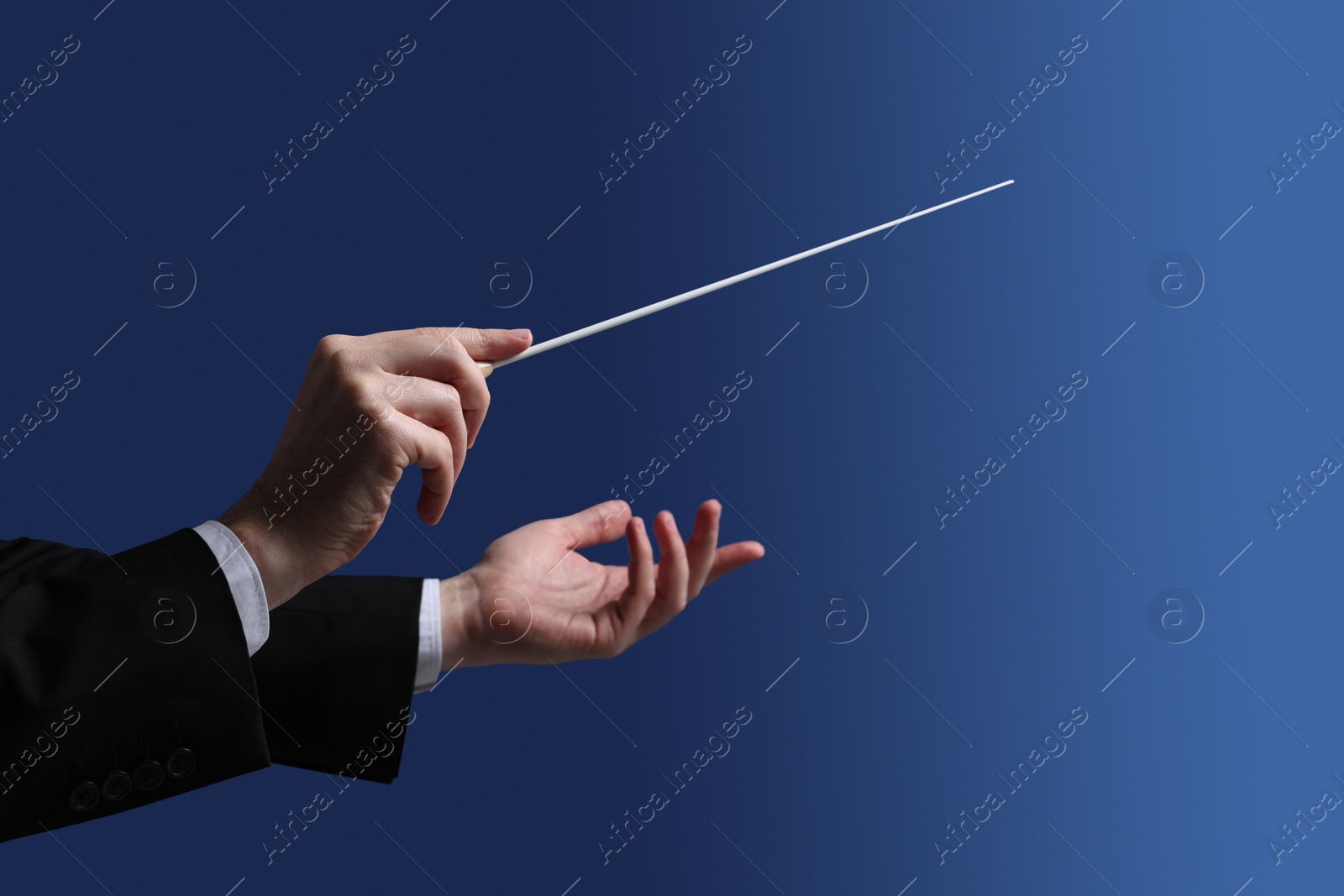 Photo of Professional conductor with baton on blue background, closeup