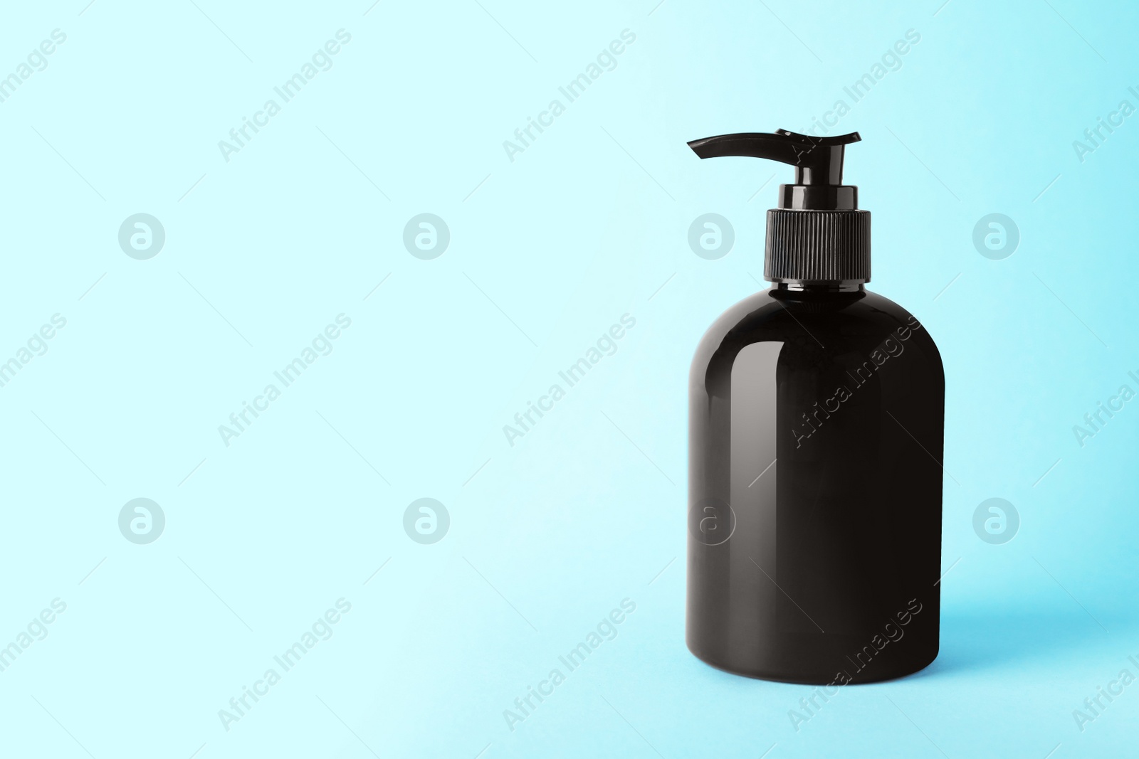 Photo of Bottle of shampoo on light blue background, space for text