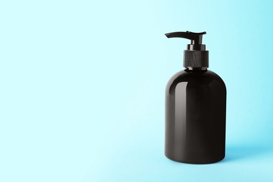 Photo of Bottle of shampoo on light blue background, space for text