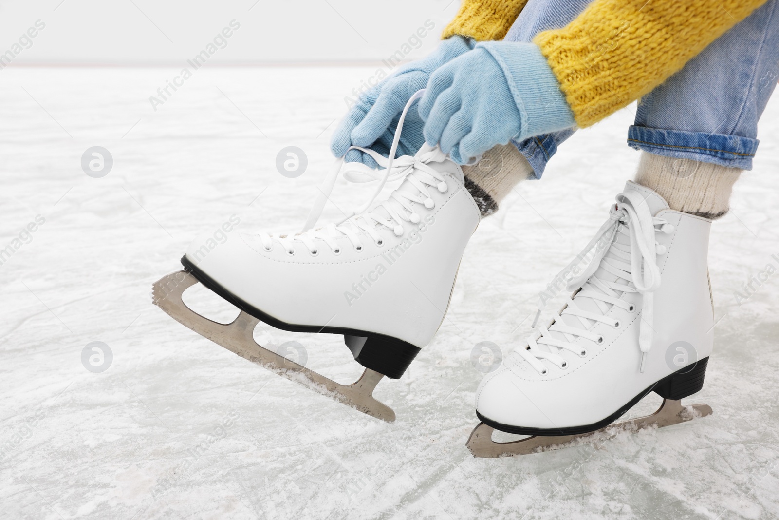 Photo of Woman lacing figure skates on ice rink, closeup