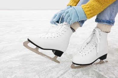 Photo of Woman lacing figure skates on ice rink, closeup