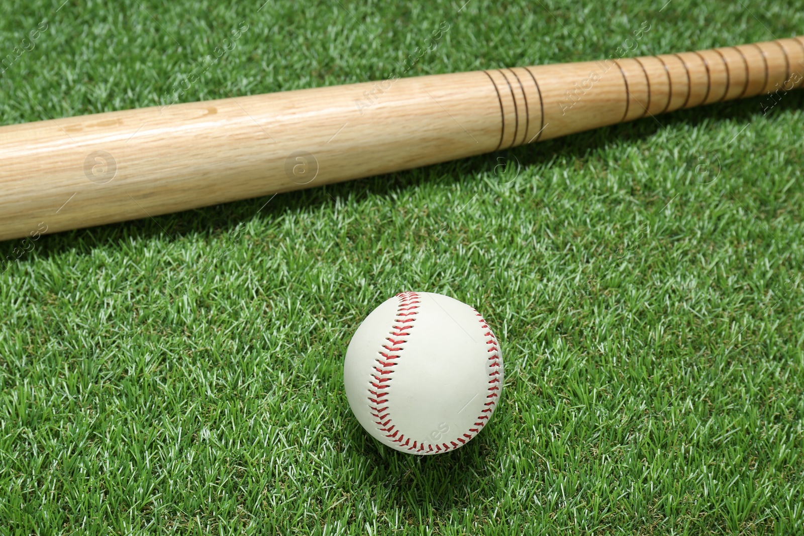 Photo of Wooden baseball bat and ball on green grass. Sports equipment