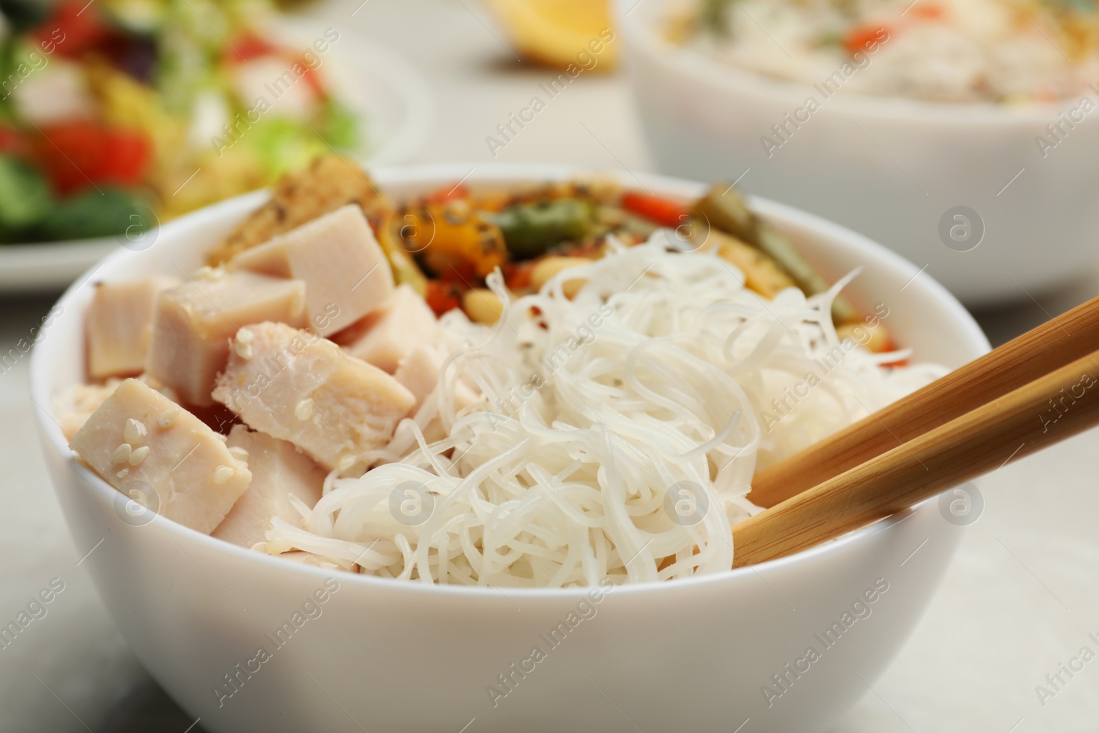 Photo of Tasty cooked rice noodles with chicken and vegetables on table, closeup