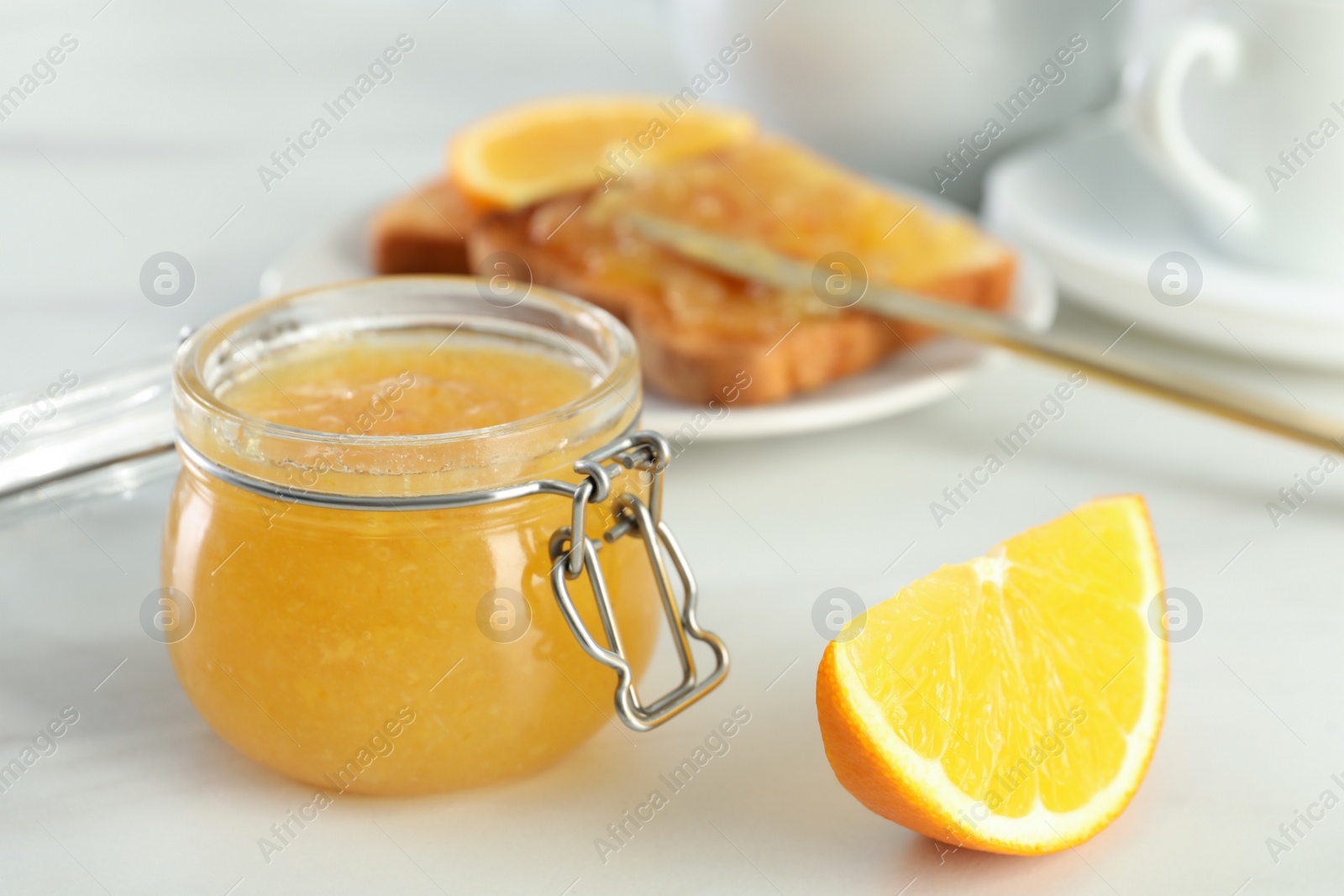 Photo of Delicious orange marmalade and citrus fruit slice on white table. Space for text