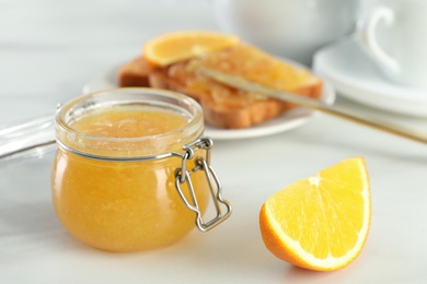 Delicious orange marmalade and citrus fruit slice on white table. Space for text