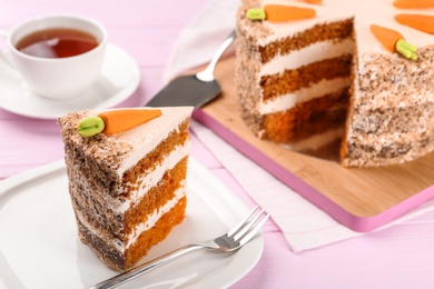 Photo of Sweet carrot cake with delicious cream on pink wooden table