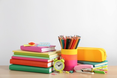 Different school stationery and alarm clock on table against white background, space for text. Back to school