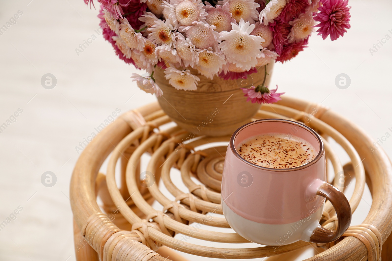 Photo of Cup of fresh coffee and beautiful bouquet on wooden stand. Good morning