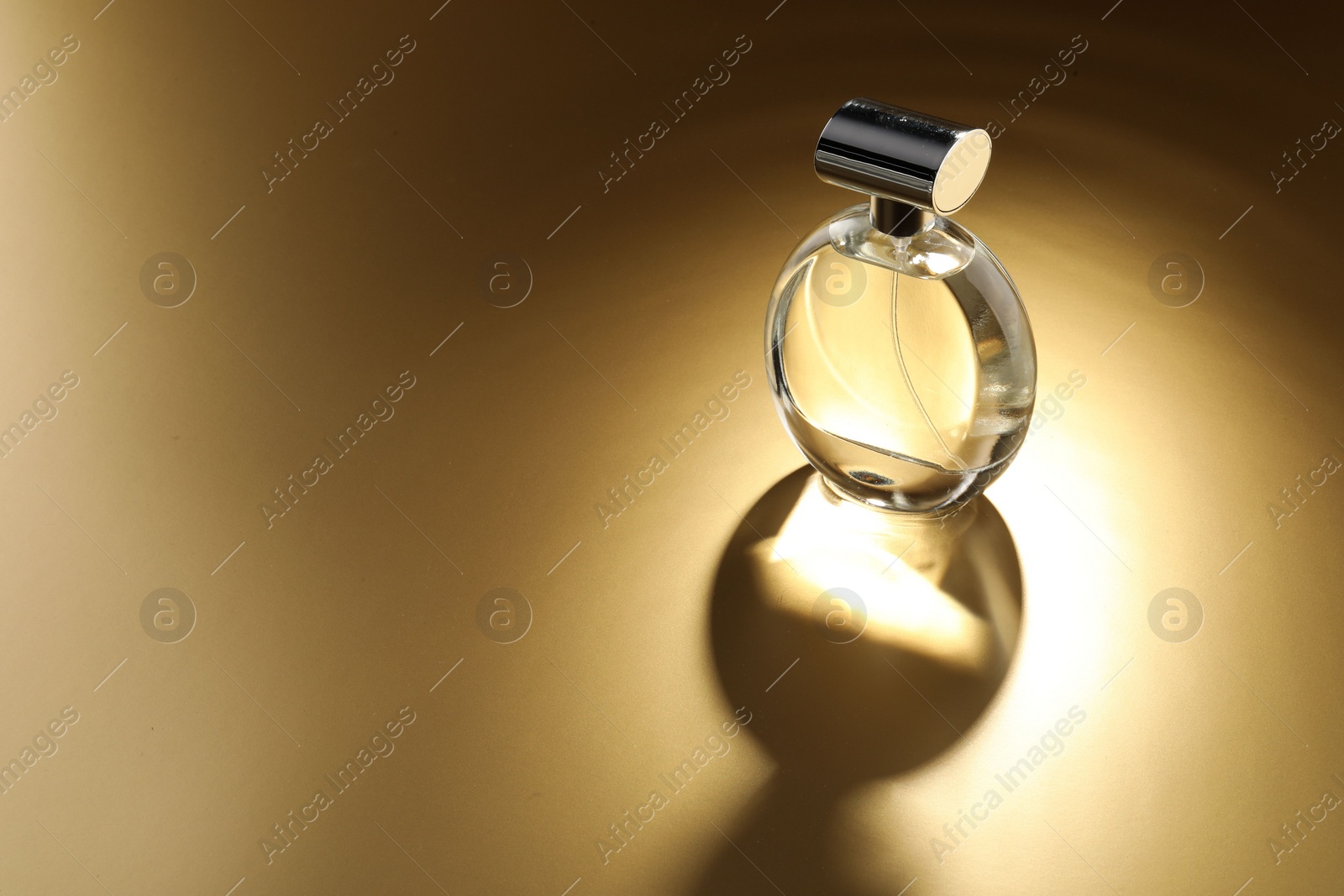 Photo of Luxury women's perfume. Sunlit glass bottle on golden background, space for text