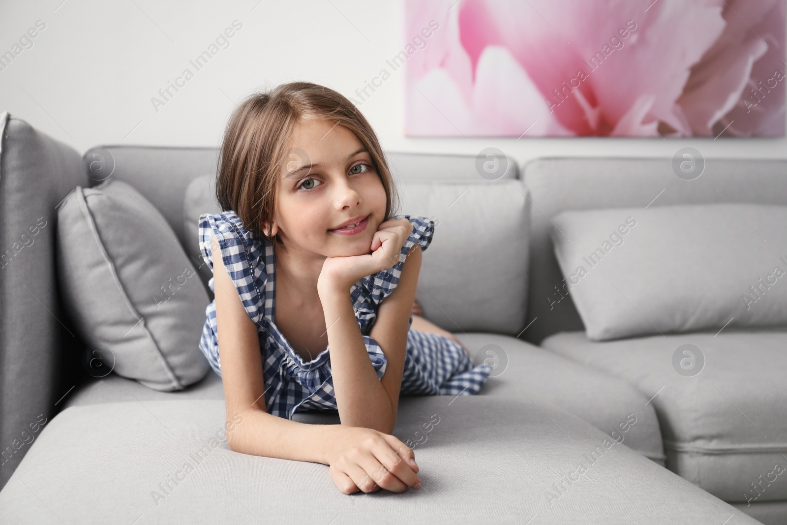 Photo of Cute little girl lying on sofa in room