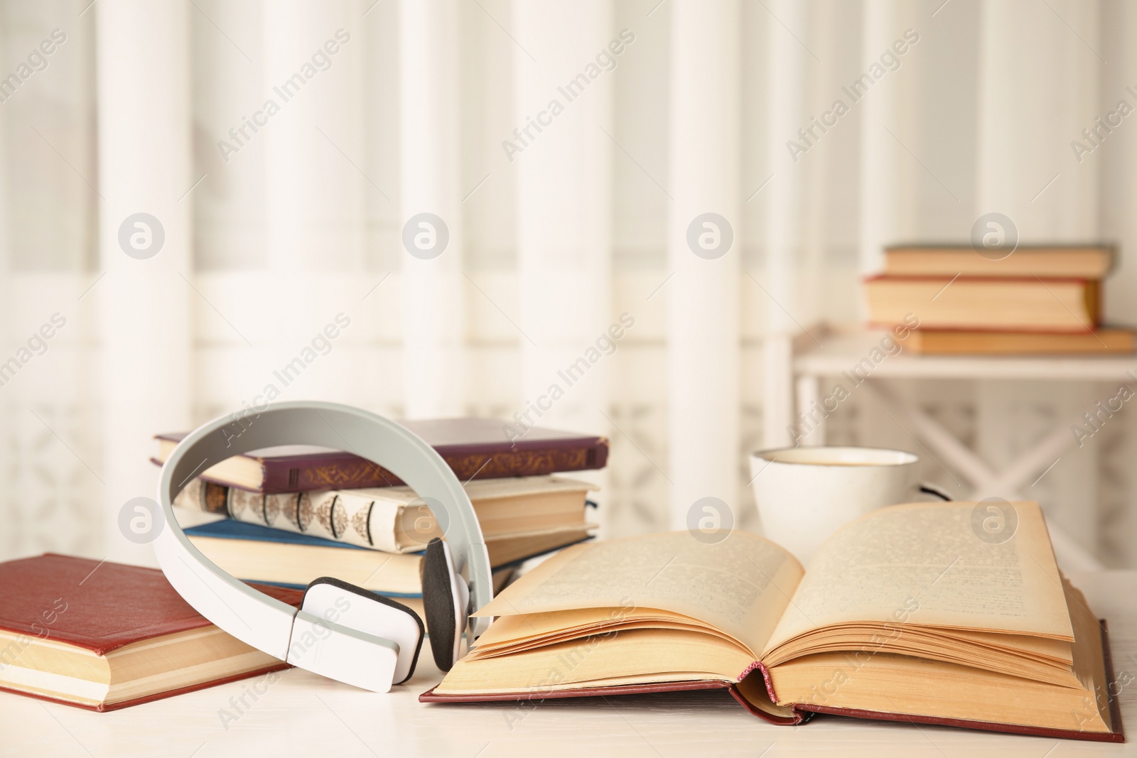 Photo of Open book and headphones on white wooden table