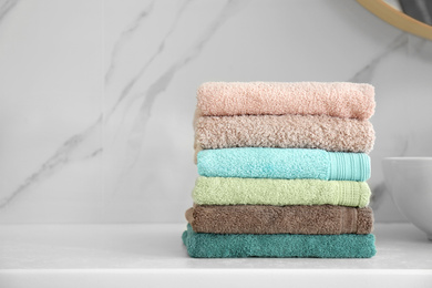 Photo of Stack of fresh towels on white countertop in bathroom. Space for text