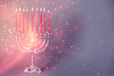 Image of Silver menorah with burning candles on color background, space for text. Hanukkah celebration