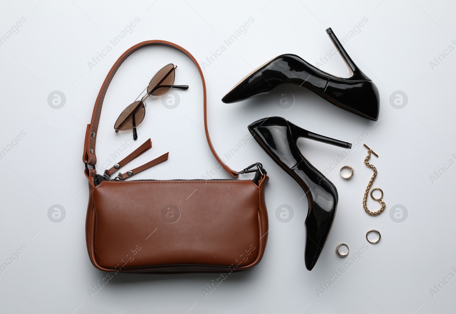 Photo of Stylish woman's bag, shoes, sunglasses and bijouterie on light background, flat lay