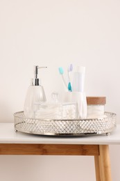 Different bath accessories and personal care products on table near white wall