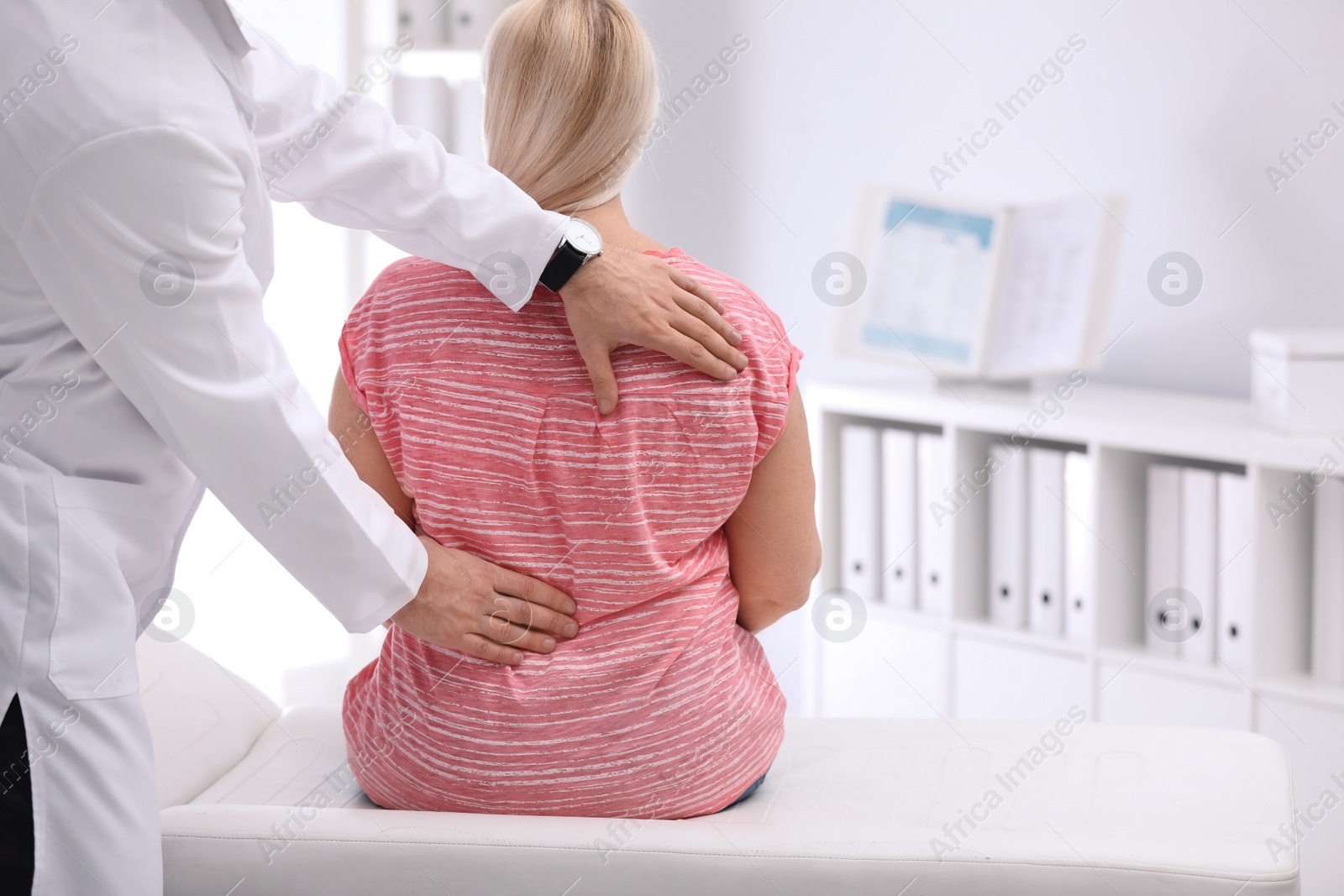 Photo of Chiropractor examining patient with back pain in clinic