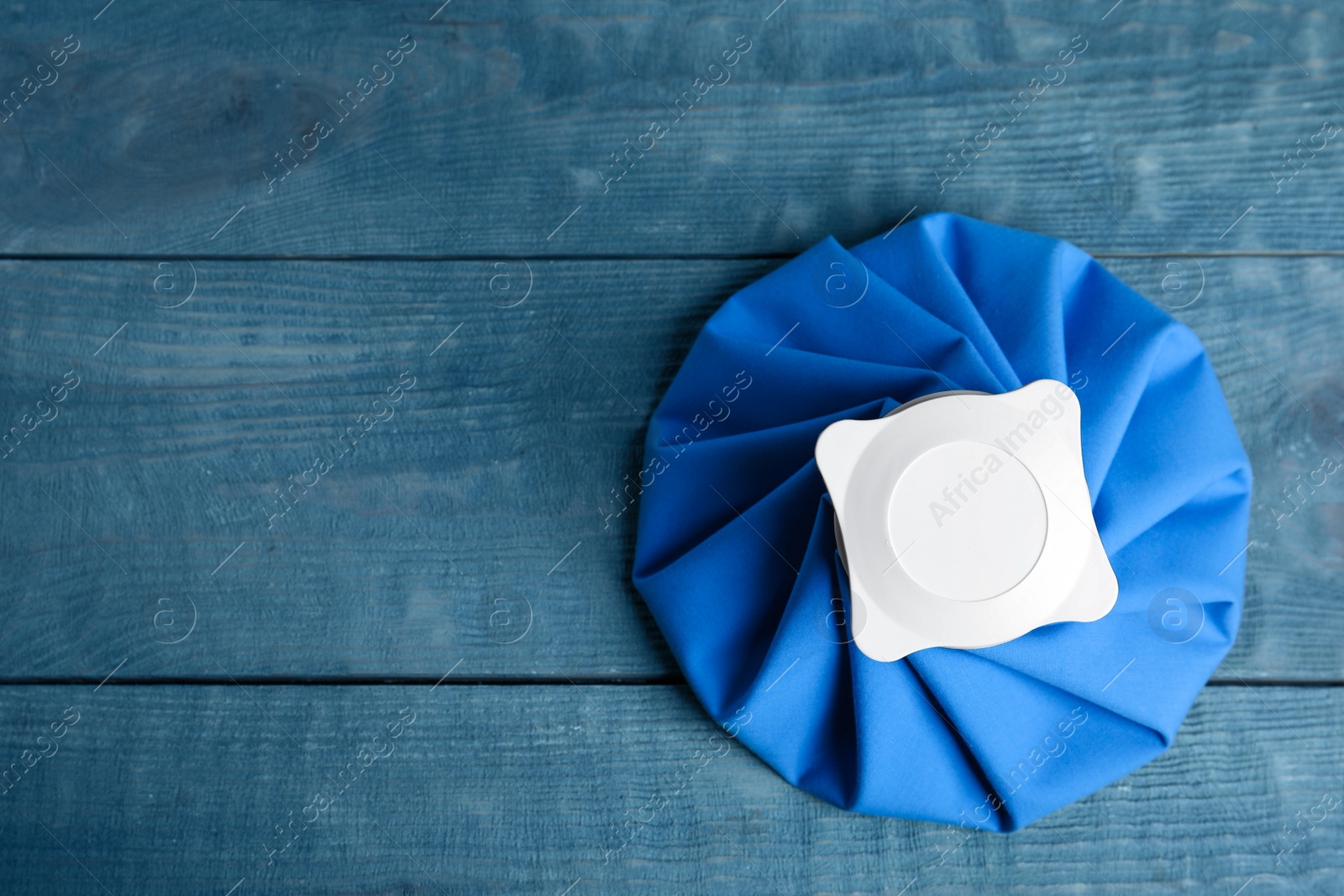 Photo of Ice pack on blue wooden table, top view. Space for text