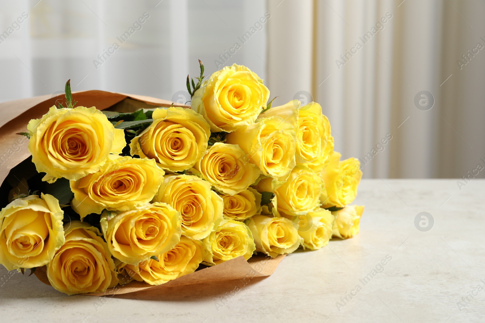 Photo of Beautiful bouquet of yellow roses on light grey table. Space for text