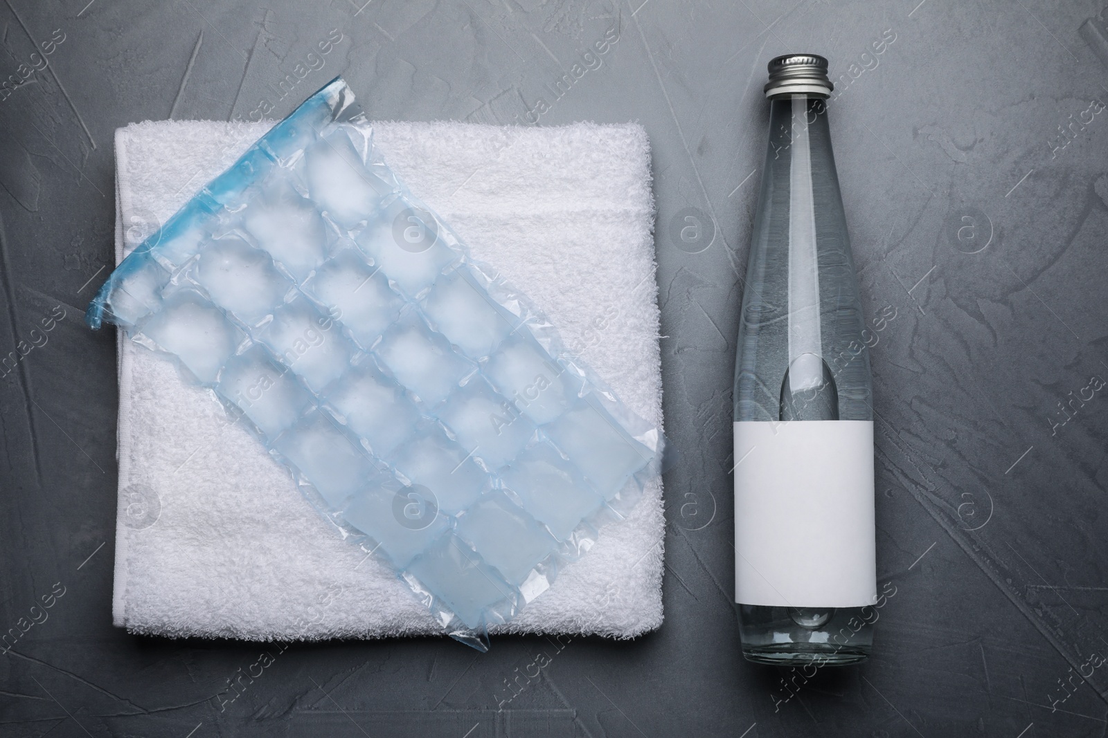 Photo of Bottle of water, ice pack and towel on grey background, flat lay. Heat stroke treatment