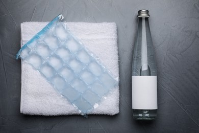 Photo of Bottle of water, ice pack and towel on grey background, flat lay. Heat stroke treatment