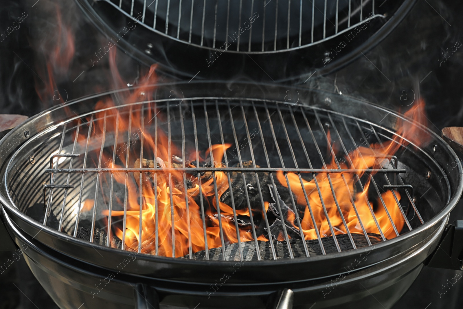 Photo of New modern barbecue grill with burning firewood, closeup