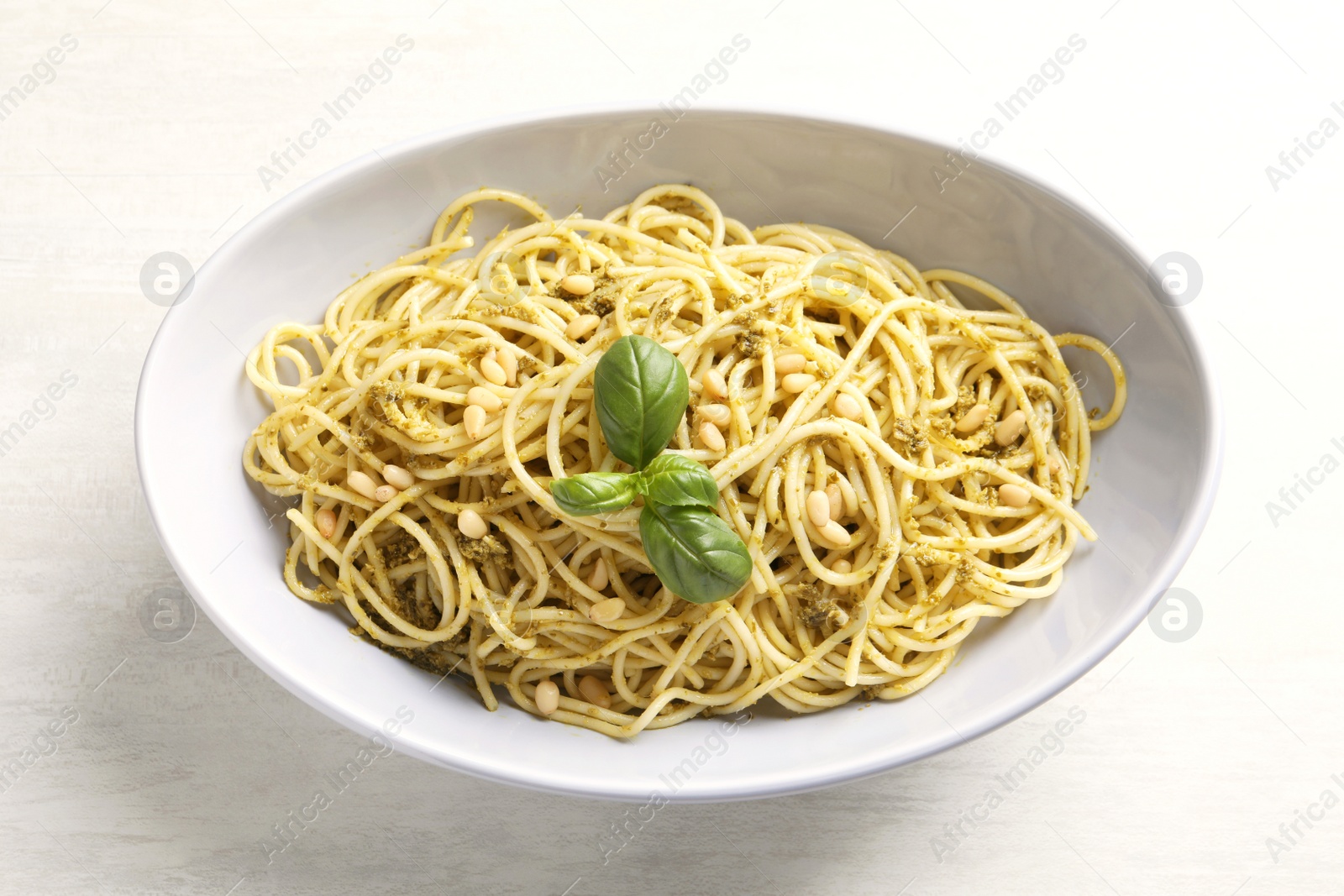 Photo of Plate of delicious basil pesto pasta on white background, top view