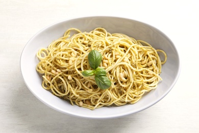 Photo of Plate of delicious basil pesto pasta on white background, top view