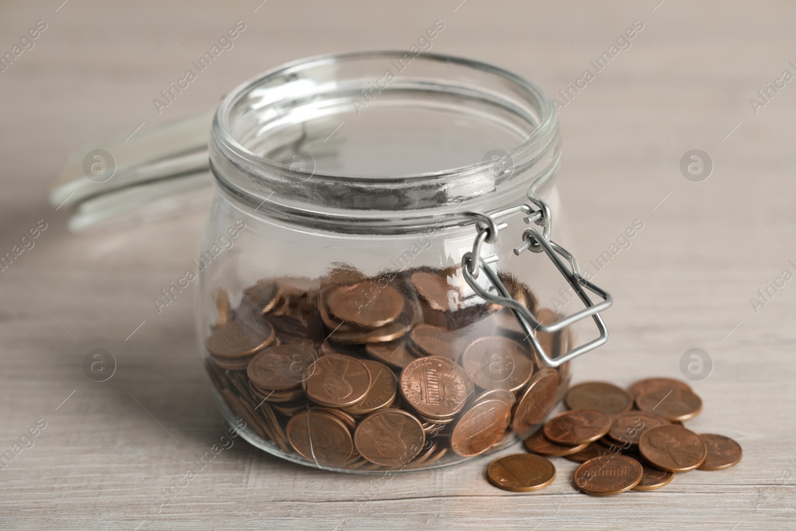 Photo of Glass jar with coins on white wooden table, closeup