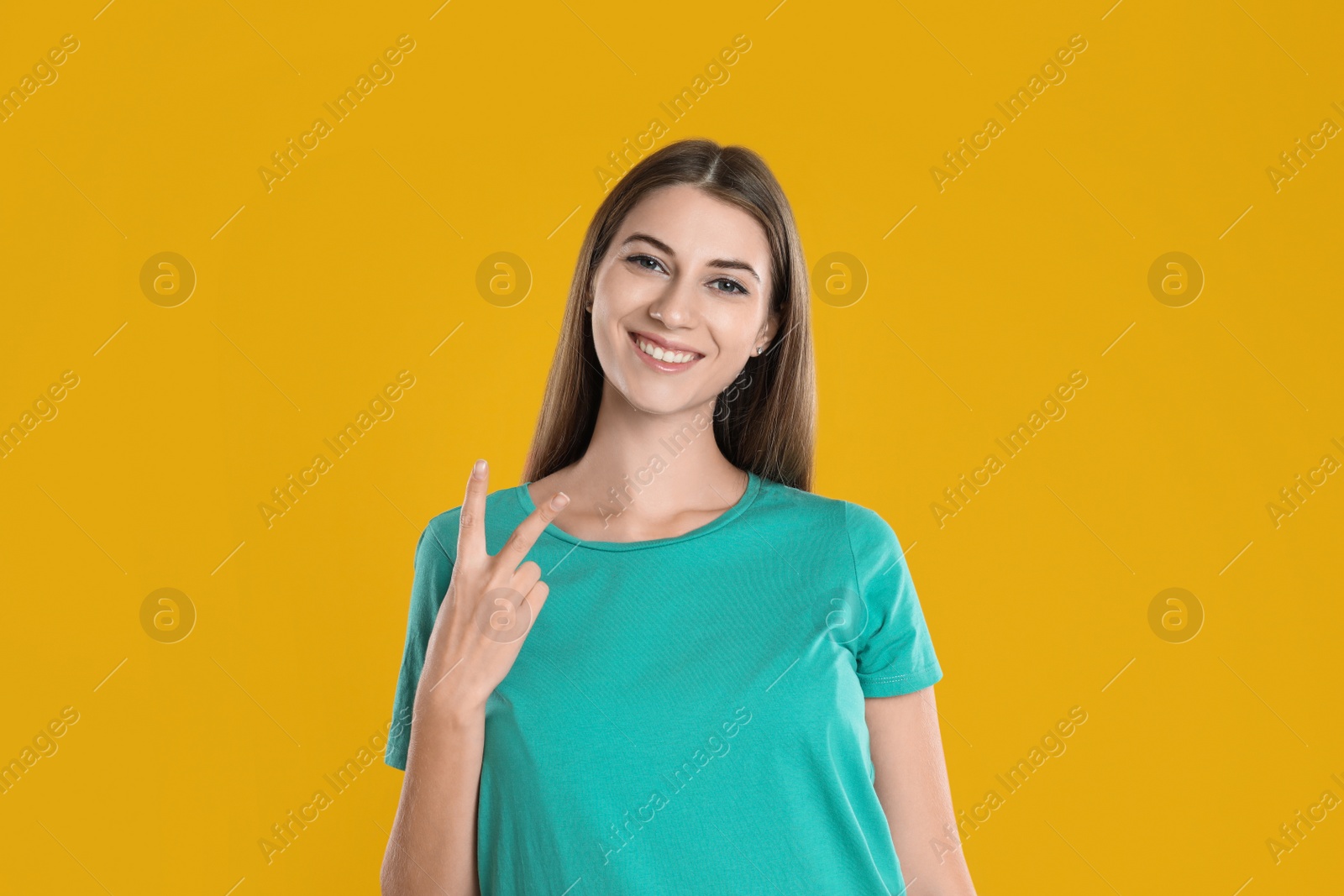 Photo of Woman showing number two with her hand on yellow background