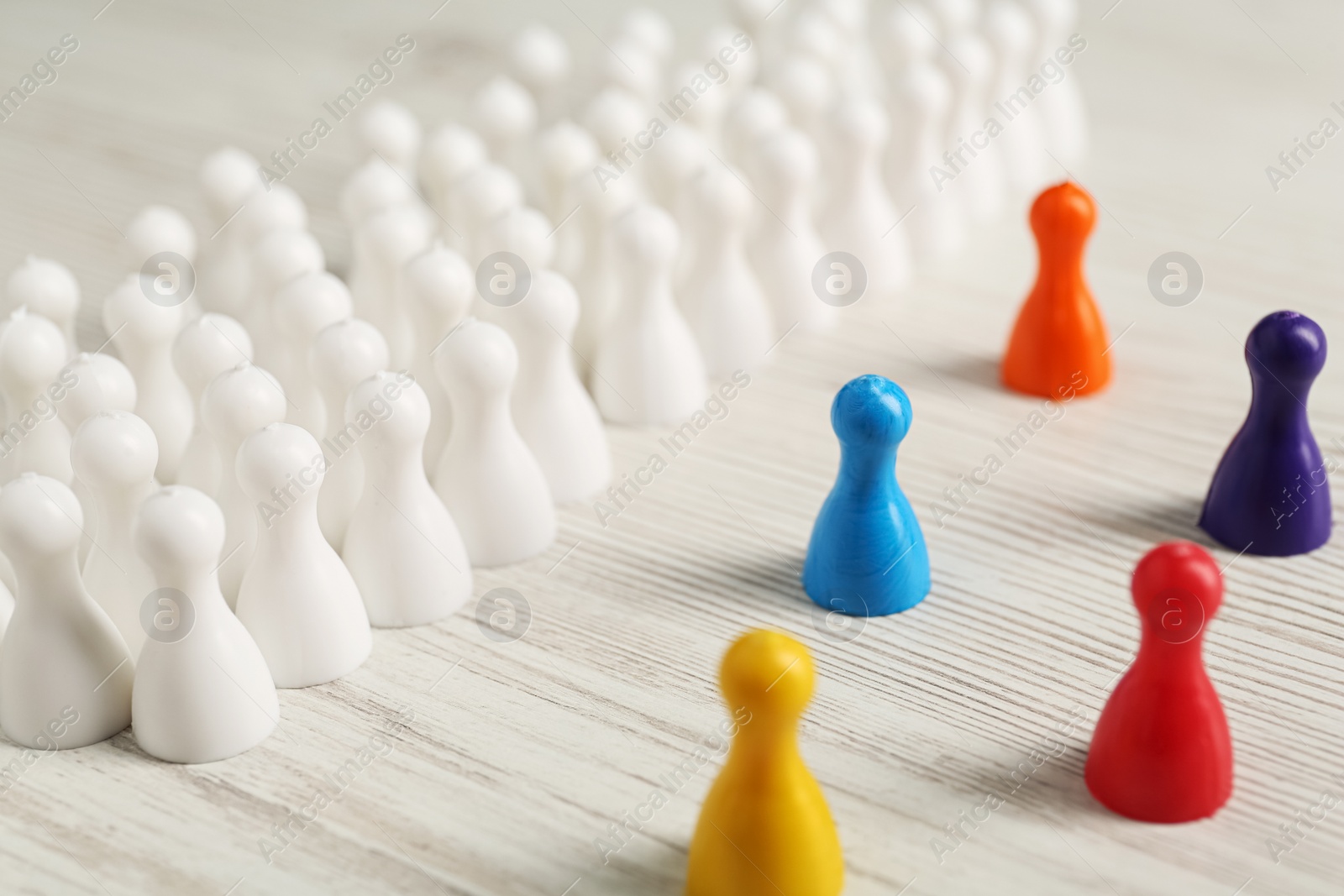 Photo of Colorful pawns on white wooden table, closeup. Social inclusion concept