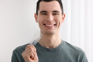 Photo of Young man with whitening strips on light background