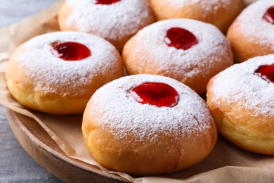 Photo of Hanukkah doughnuts with jelly and sugar powder on grey table, closeup