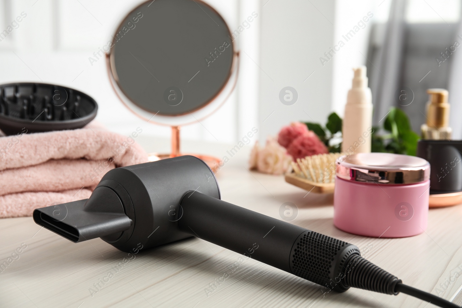 Photo of Hair care product and dryer on white wooden table