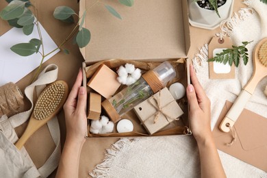 Photo of Woman with eco friendly personal care products at brown table, top view