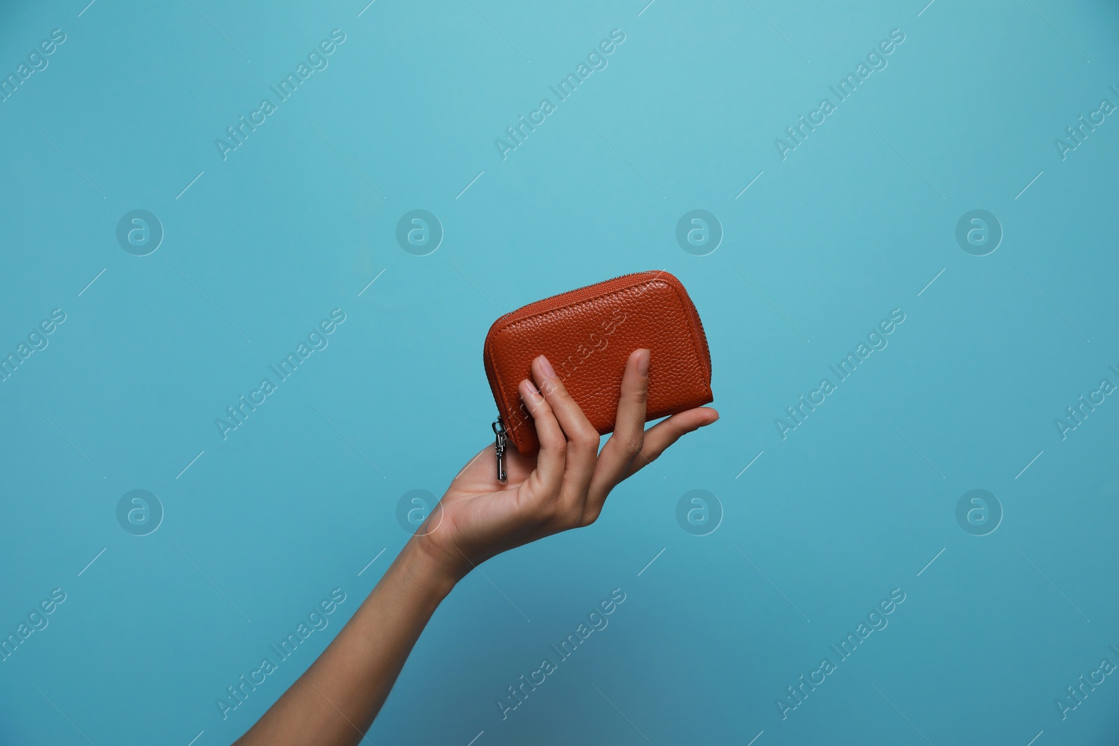 Photo of Woman holding leather purse on light blue background, closeup. Space for text