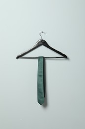 Photo of Hanger with green necktie on light grey wall