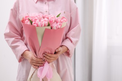Woman with bouquet of beautiful fresh tulips on blurred background, closeup