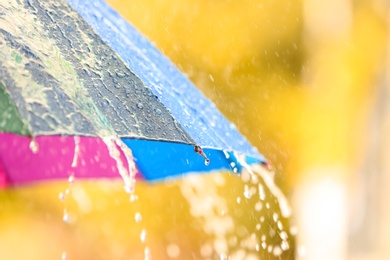 Photo of Bright color umbrella under rain outdoors, closeup