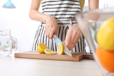 Photo of Young woman preparing lemonade on table, closeup. Natural detox drink