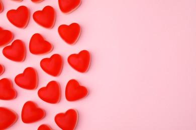 Delicious heart shaped jelly candies on pink background, flat lay. Space for text