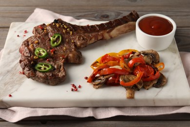 Delicious fried beef meat served with vegetables and sauce on wooden table