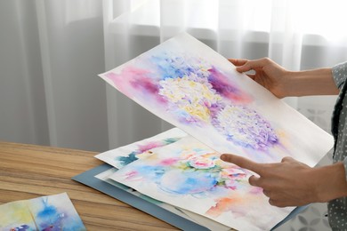 Woman holding painting of flowers indoors, closeup. Watercolor artwork