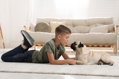 Photo of Boy with his cute pug lying on floor in living room