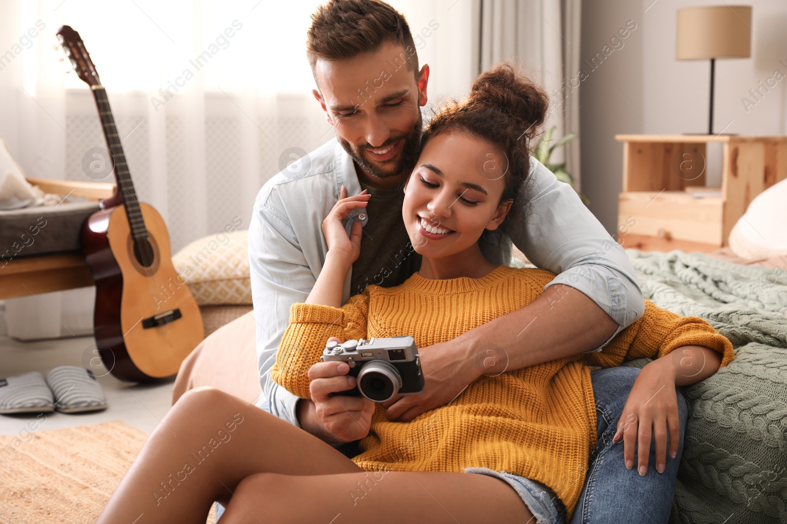 Photo of Lovely couple with camera on floor in bedroom