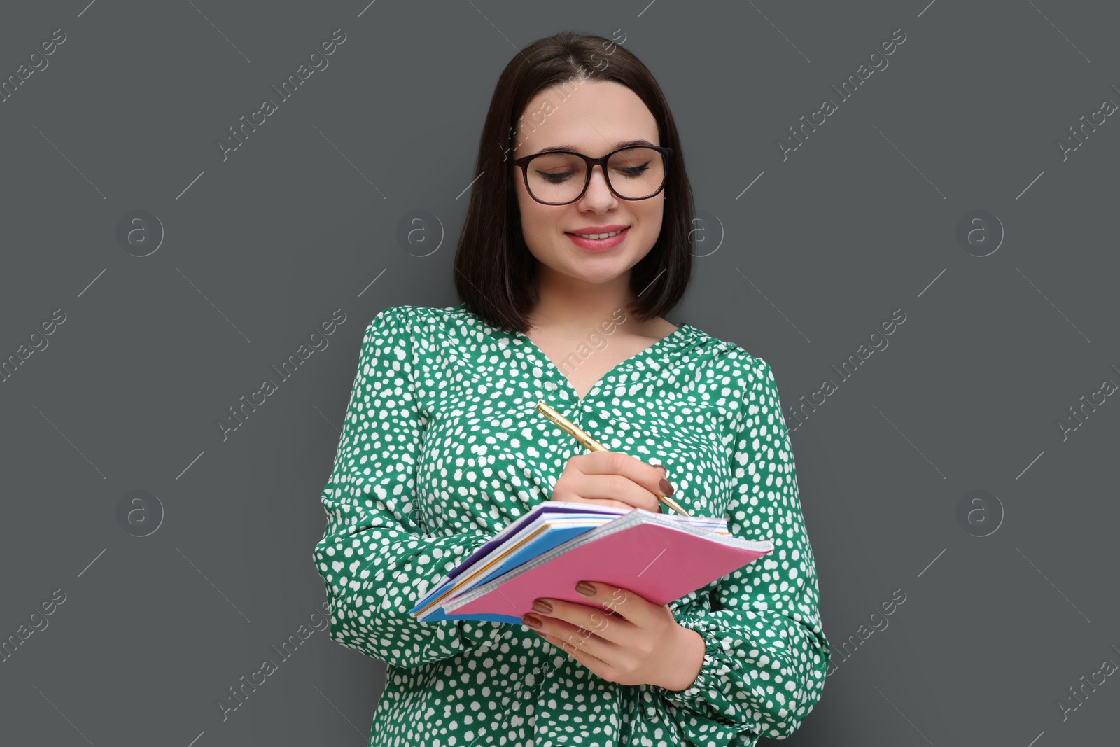 Photo of Happy young intern with notebooks and pen on grey background